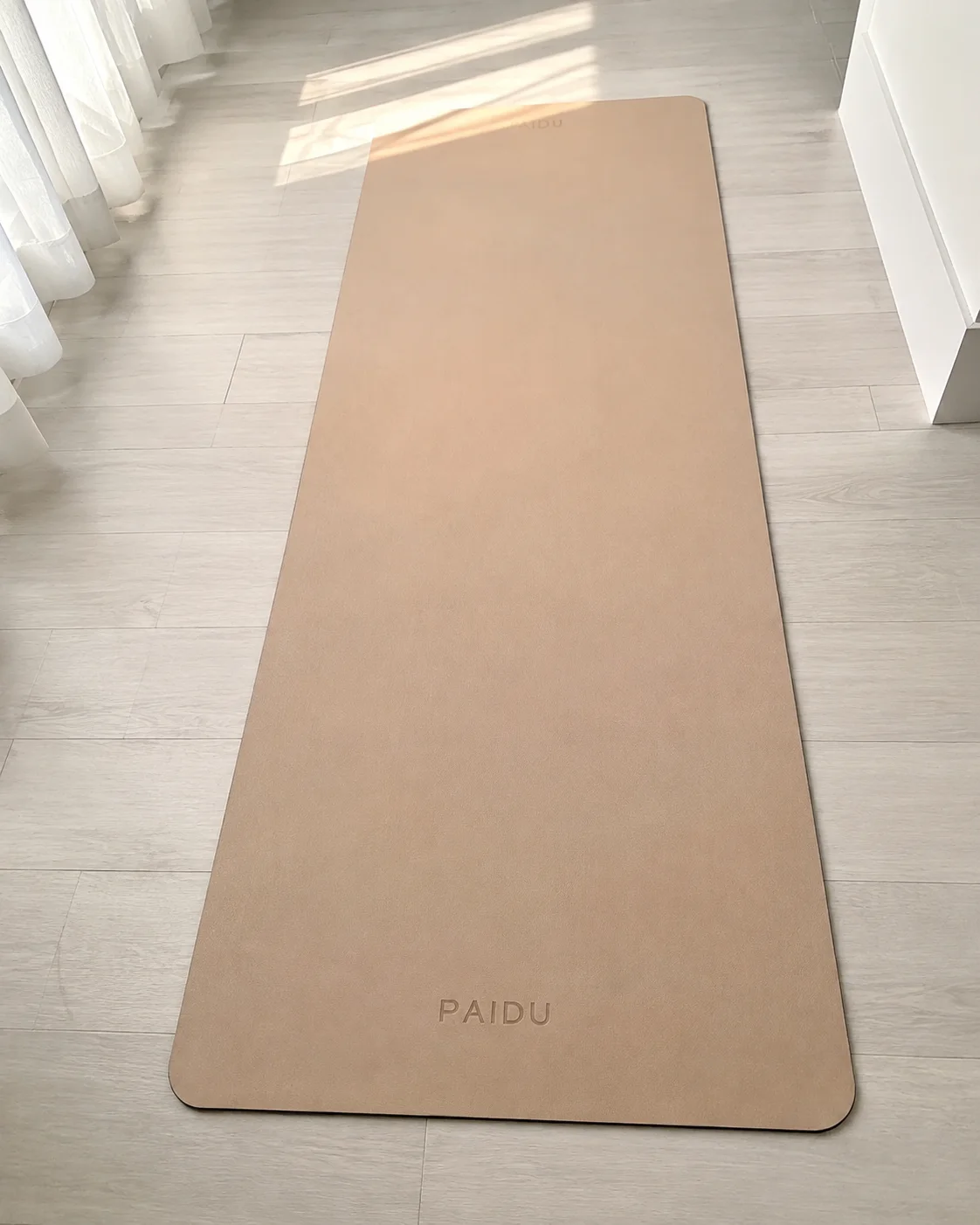 Foto original del vendedor: el tapete de yoga PAIDU tendido en el piso de un cuarto, con la luz de la ventana.