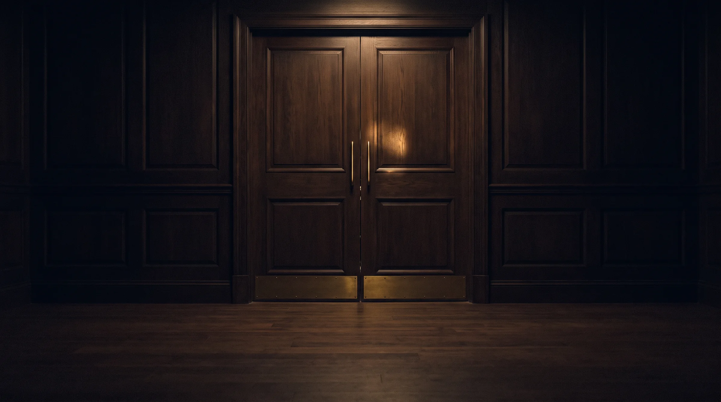 La puerta del salón: doble hoja de madera oscura con herrajes y zócalo de latón